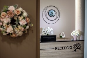 A reception desk with a floral arrangement, a mirror, and a wooden cabinet labeled "RECEPCIÓN". - Árnyas Panzió Gödöllő (Gödöllő)