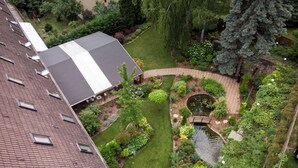 A rooftop garden with a pond, a small bridge, and a variety of plants and trees. - Árnyas Panzió Gödöllő (Gödöllő)