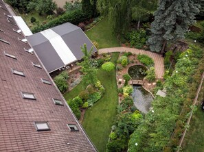 Un jardín en la azotea con un estanque, un pequeño puente y una variedad de plantas y árboles.
