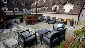 A patio with outdoor furniture, a wooden barrel, and a garden area with plants. - Árnyas Panzió Gödöllő (Gödöllő)