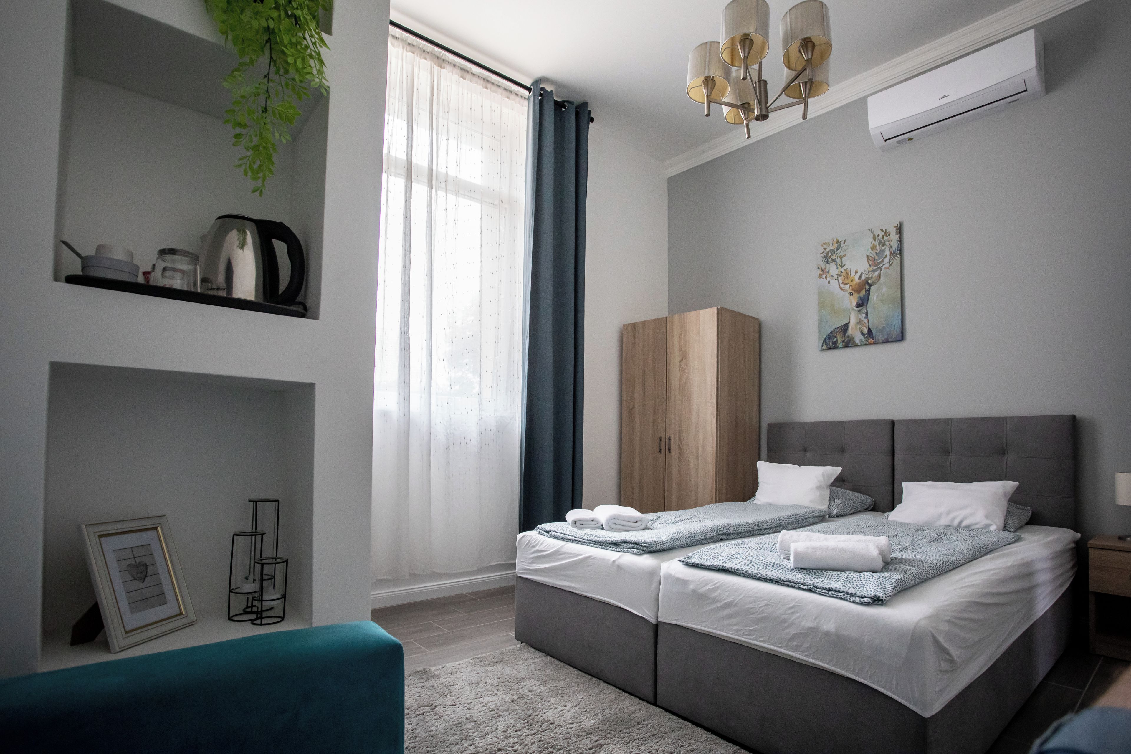 A modern bedroom with a double bed, a wardrobe, a bedside table, and a hanging plant.