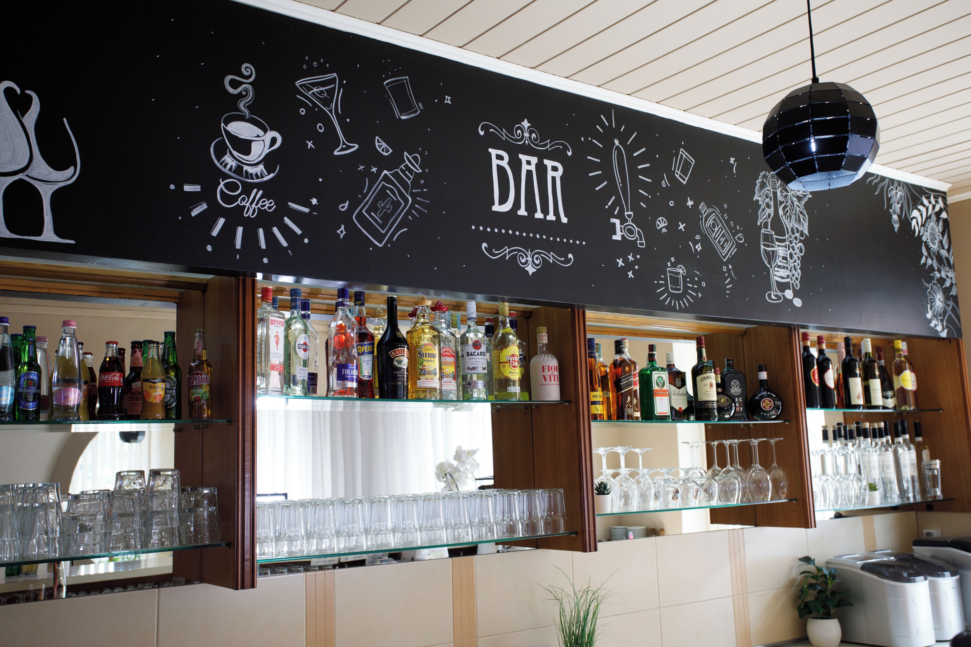 Um bar com prateleiras cheias de garrafas de bebidas e copos.