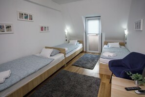 A small, modern room with three single beds, a desk with a chair, and a small potted plant. - Árnyas Panzió Gödöllő (Gödöllő)