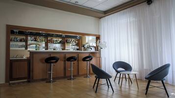 A bar area with a counter, stools, and a view of the outside through large windows.