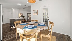 Un coin repas avec une table ronde, des chaises en bois et un luminaire suspendu.