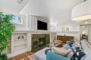 Un salon spacieux doté d’une cheminée, d’étagères intégrées, d’un téléviseur et d’un coin salon confortable.