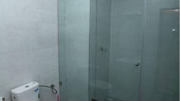 A bathroom with a toilet, a glass-enclosed shower, and a checkered floor.