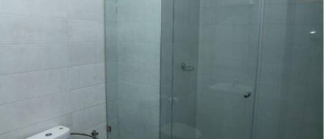 A bathroom with a toilet, a glass-enclosed shower, and a checkered floor.