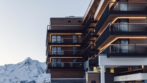 A multi-story hotel with balconies and a mountain backdrop. - Hotel Schöne Aussicht (Soelden)