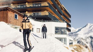 A modern ski resort building with multiple balconies and a ski slope in the foreground. - Hotel Schöne Aussicht (Soelden)