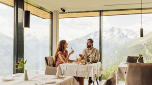 A dining area with a table set for two, overlooking a mountainous landscape. - Hotel Schöne Aussicht (Soelden)