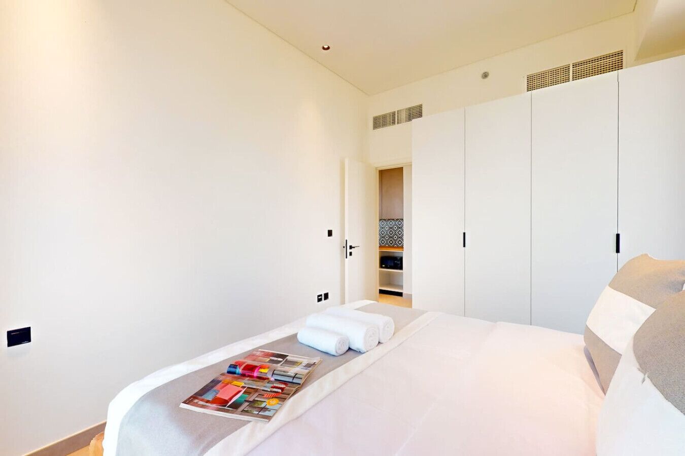 Een hotelkamer met een bed, een tijdschrift en een kledingkast.