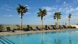Una piscina con palmeras y sillones de descanso.