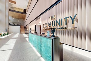 Un área de recepción moderna con mostrador, un cartel que dice "The Community" y una escalera al fondo.