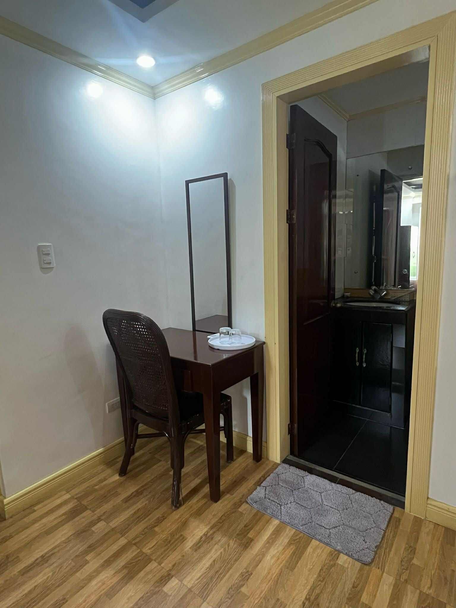 Una habitación con una mesa de comedor de madera, una silla marrón oscuro, un tapete pequeño y una puerta que da a una zona de cocina.