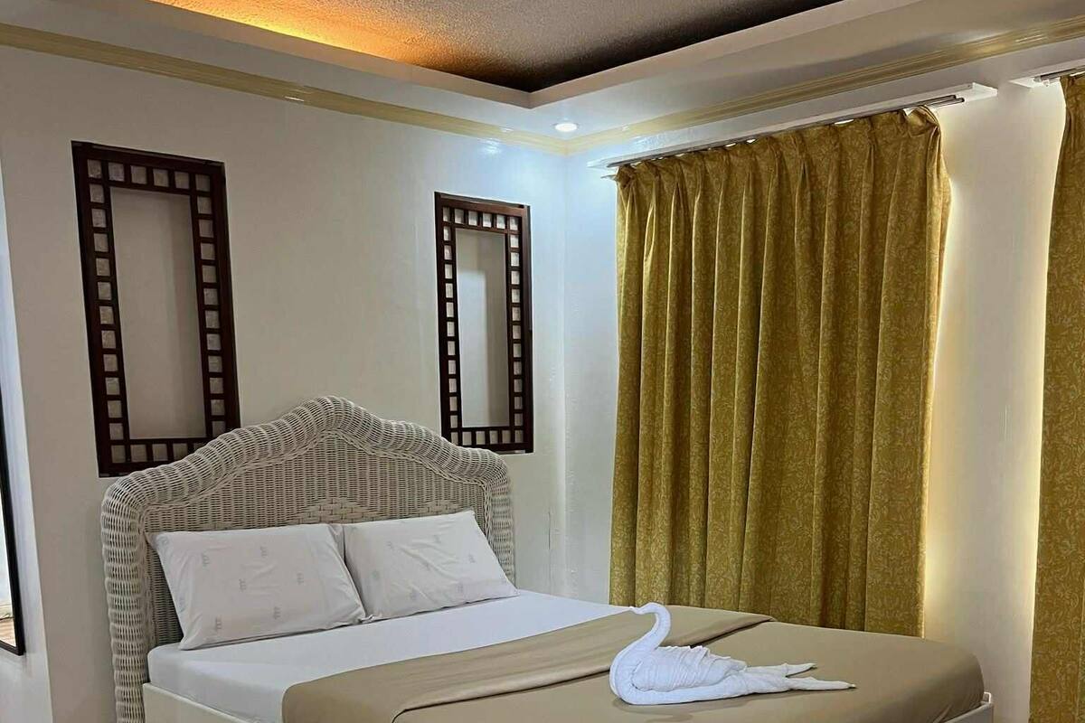 Ein modernes Hotelzimmer mit einem großen Bett, zwei Wandspiegeln und einem Fenster mit Vorhängen.