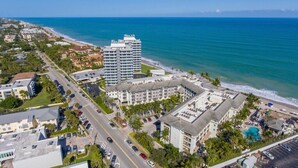 Eine Luftaufnahme eines Küstenhotels mit mehreren Gebäuden, einem Parkplatz und einem Strand.