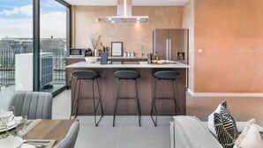 Een moderne keuken met een groot eiland, barstoelen en uitzicht op de stad.
