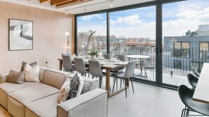 Een moderne woonkamer met een eethoek, grote ramen en uitzicht op de stad.