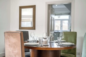 A dining table set with plates, glasses, and cutlery, surrounded by chairs. - Beautiful 2 bedroom attic behind Harrods (Greater London)