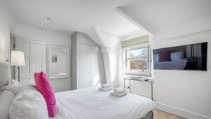 A bedroom with a bed, a bedside table, a lamp, a wardrobe, and a window.