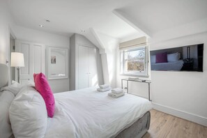 A bedroom with a bed, a bedside table, a lamp, a wardrobe, and a window.