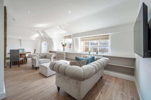 Ein geräumiges Loft mit hohen Decken, einem Essbereich, einer Sofagarnitur und einem großen Fenster mit Blick.