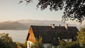 Une maison avec un toit en pente, une cheminée et une vue sur les montagnes en arrière-plan.