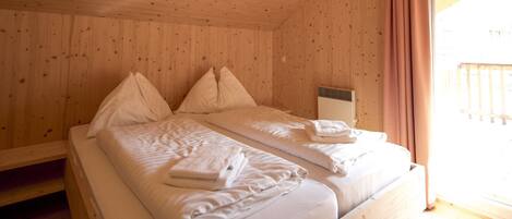 Un dormitorio de cabaña de madera con cama, almohadas y una ventana con cortinas.