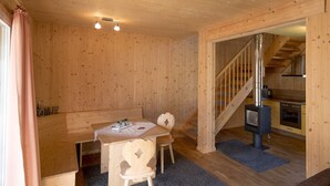 Um interior em madeira com sala de jantar, escada e cozinha.