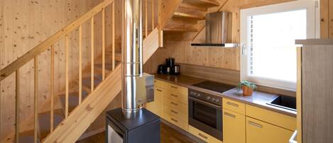 Un interior de madera con cocina, estufa y escalera.