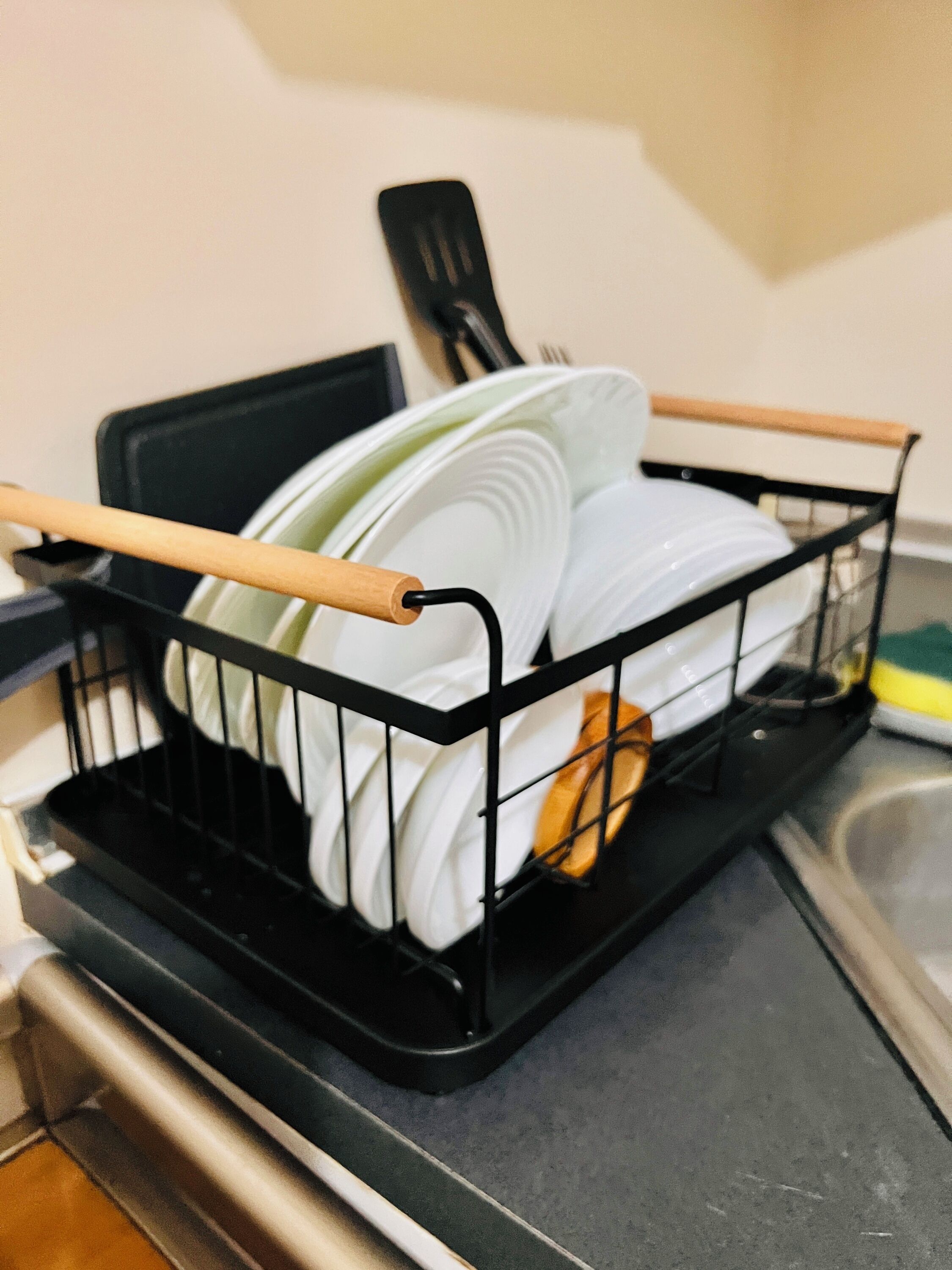 A dishwasher with a dish rack containing plates and a wooden spoon.