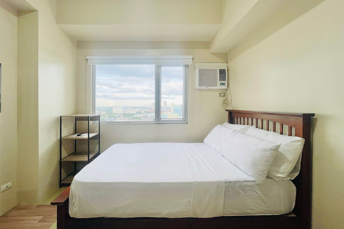 A bedroom with a bed, a window, and an air conditioning unit.