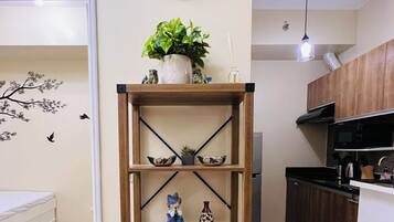 A wooden bookshelf with decorative items, a wall clock, and a potted plant in a modern living space.