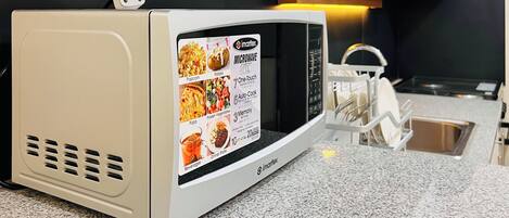 A microwave oven with a digital display listing cooking options like popcorn, pizza, and frozen vegetables.
