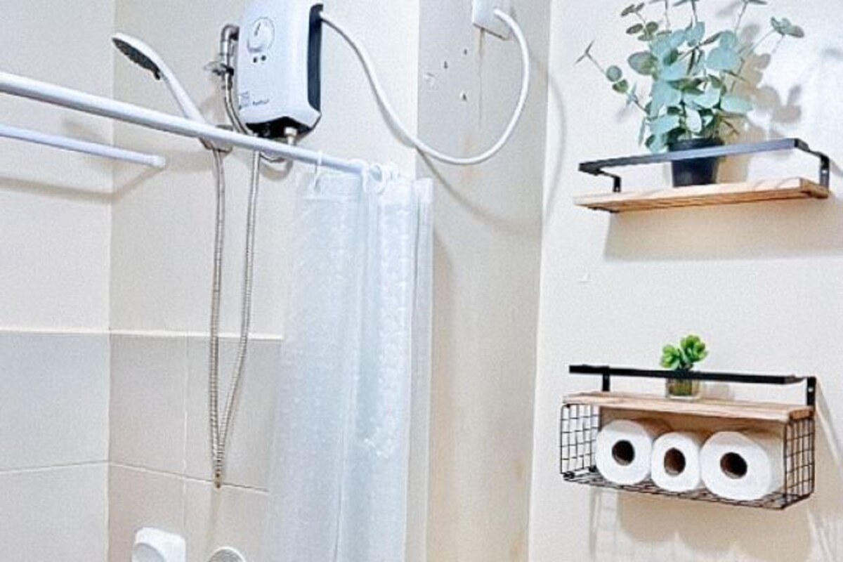 A bathroom with a shower, a towel rack, and two shelves with plants and toilet paper.