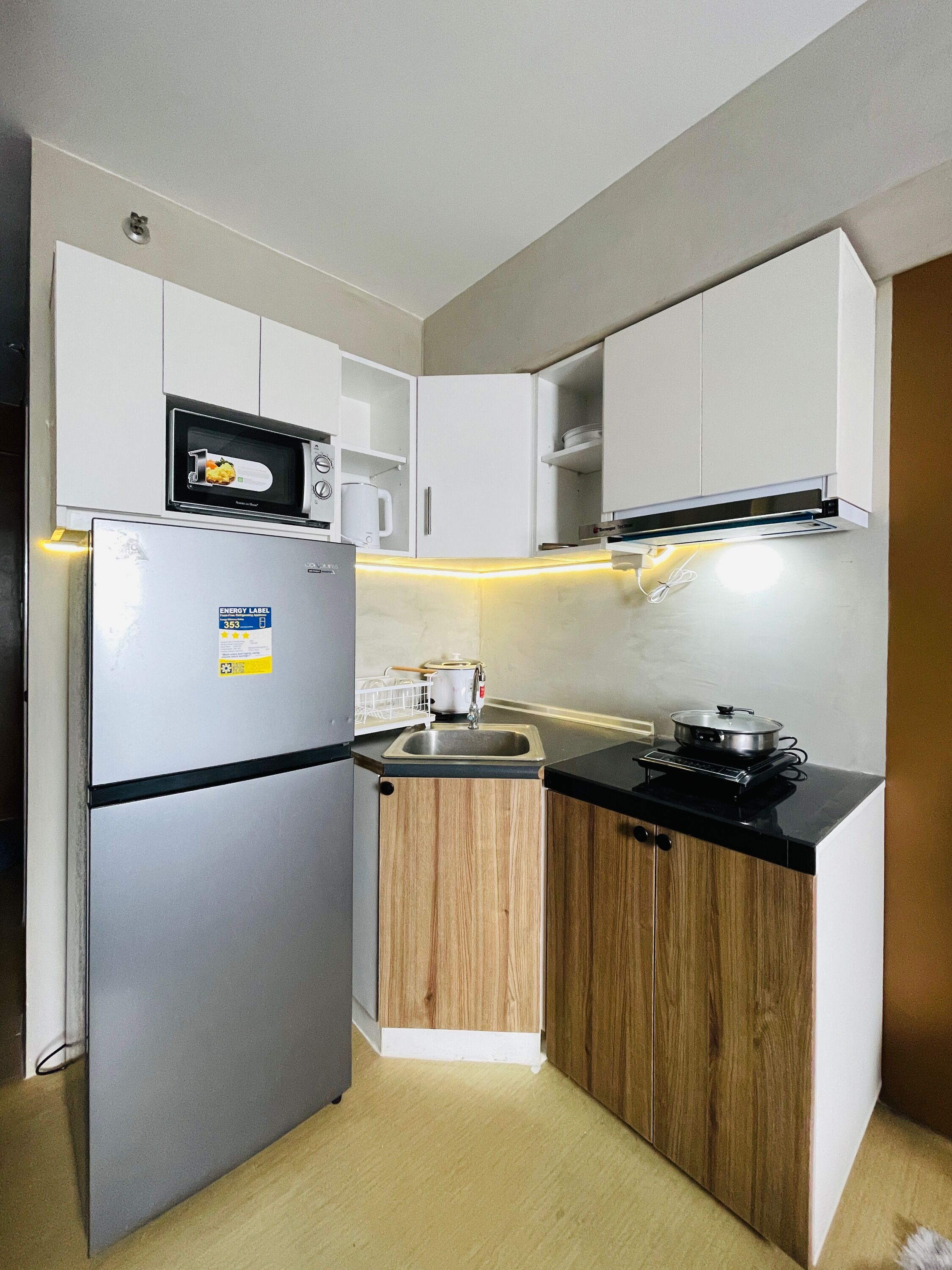 A compact kitchen with a refrigerator, microwave, stove, and wooden cabinets.