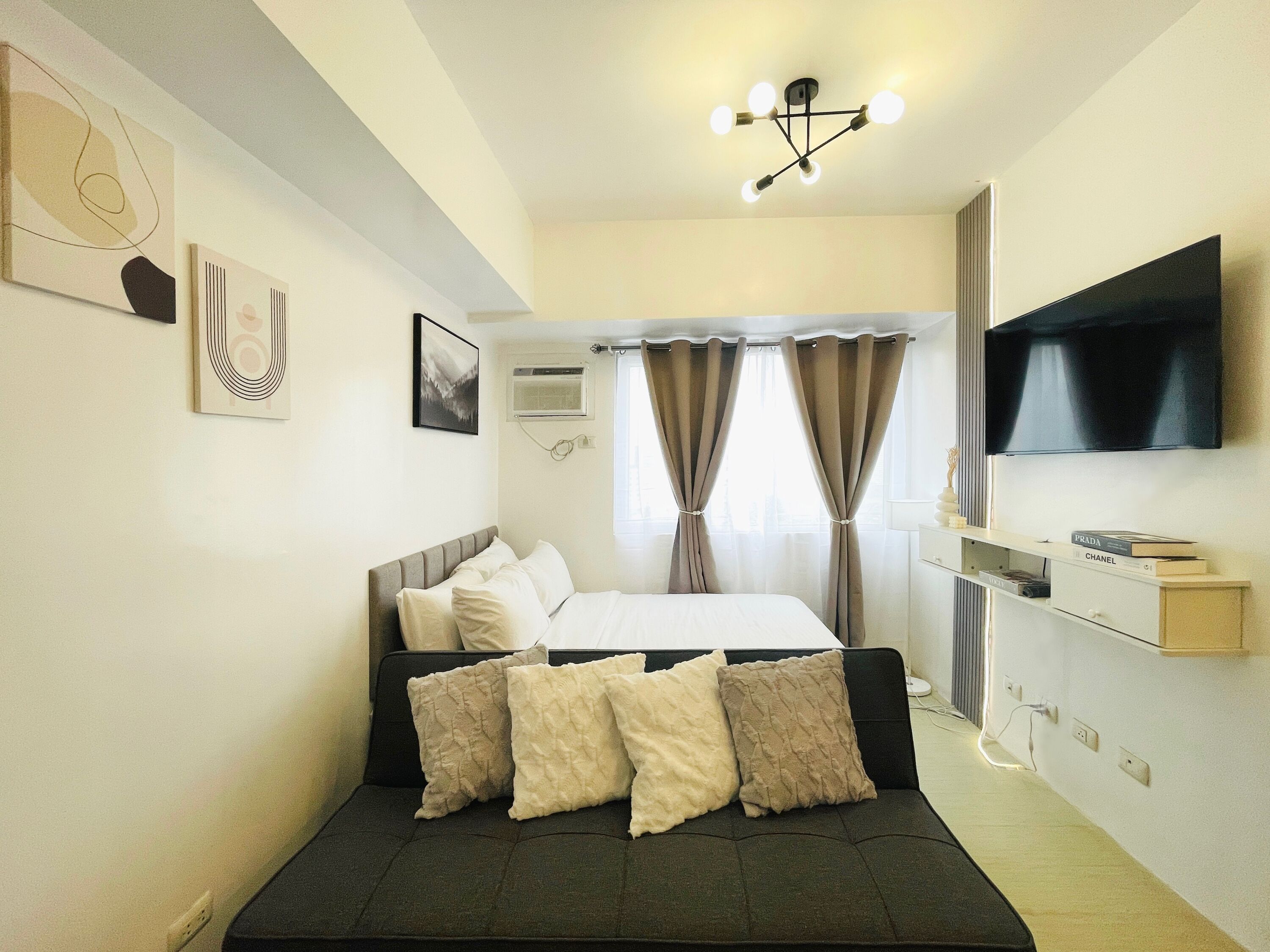 A modern bedroom with a bed, a TV, and a desk with a flat-screen TV.