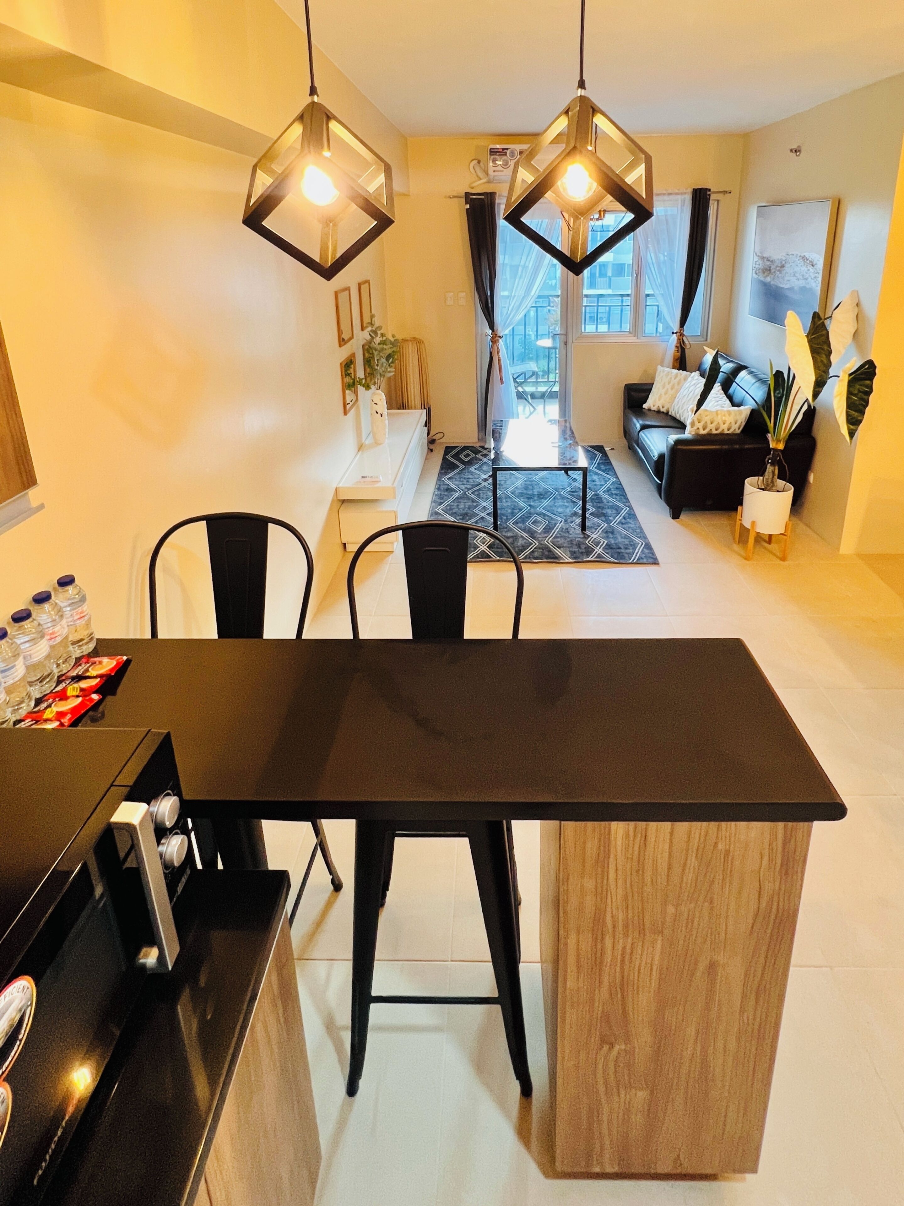 A modern kitchen with a black dining table and chairs, a built-in oven, and pendant lights.