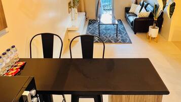 A modern kitchen with a black dining table and chairs, a built-in oven, and pendant lights.