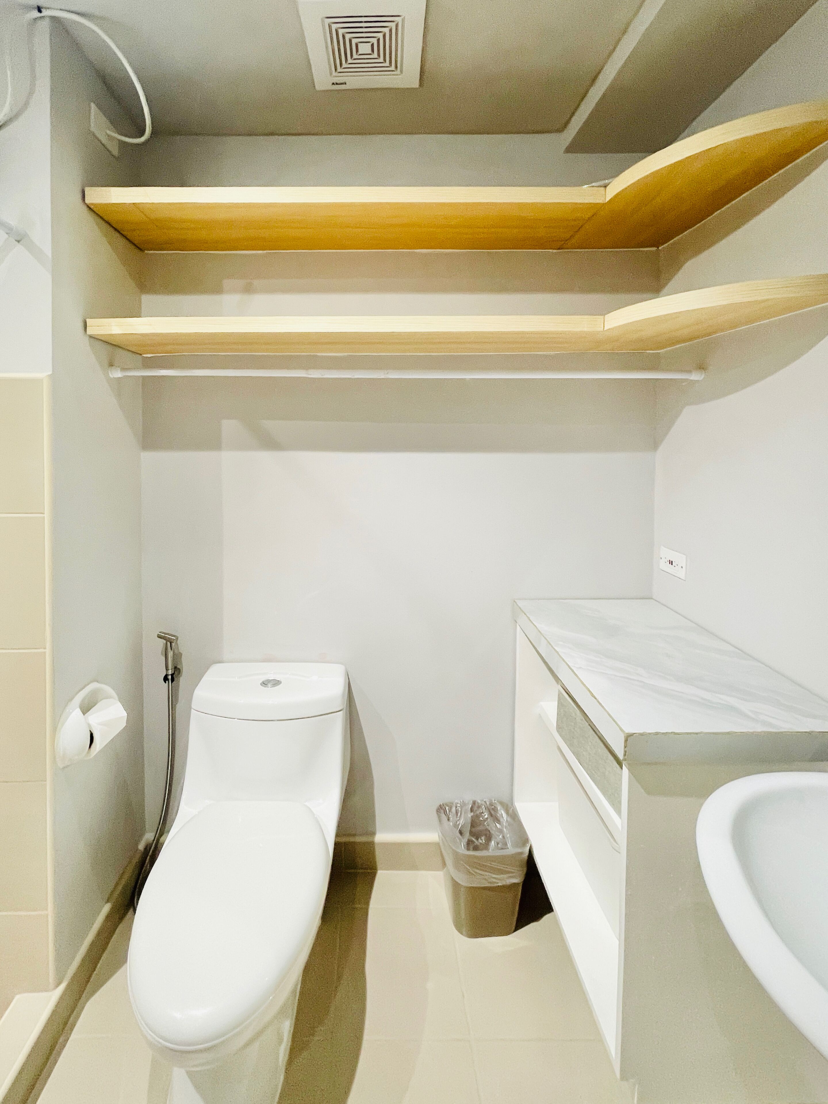 A compact bathroom with a toilet, bidet, and a small trash bin.