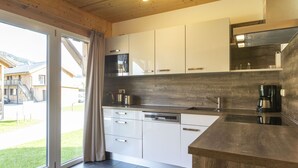 Una cocina moderna con armarios blancos, lavavajillas y cafetera.