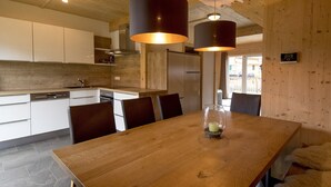Una cocina moderna con armarios blancos, encimera de madera y comedor con mesa y sillas de madera.