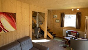 Un interno accogliente con divano, tavolo da pranzo, una scala e una stufa a legna.