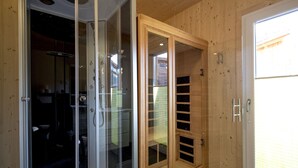 Quarto com box de vidro, porta de madeira com janela e porta de correr de vidro que dá para o exterior.