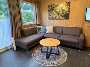 A modern living room with a sectional sofa, a round coffee table, and a large window with curtains.