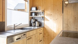 Una cucina con mobili in legno, lavello in acciaio inossidabile, una finestra e un forno a microonde integrato.