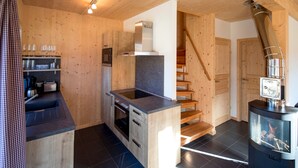 Una cucina moderna con pareti in legno, un piano cottura integrato e una scala che conduce a una mansarda.