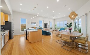 Une cuisine moderne dotée d’un îlot central, un coin repas avec une table ronde et des chaises, et un espace de vie comprenant un canapé et un téléviseur.