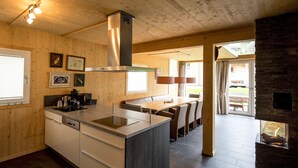 A modern kitchen with wooden walls, a central island, and a dining area with a view to the outdoors.